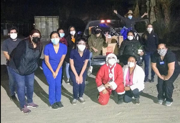 Students kneeling and posing behind a truck with gifts