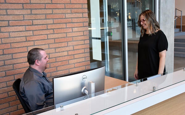 Jennifer Mitchell chats with Clark Hapeman at the front desk of SOM ED II