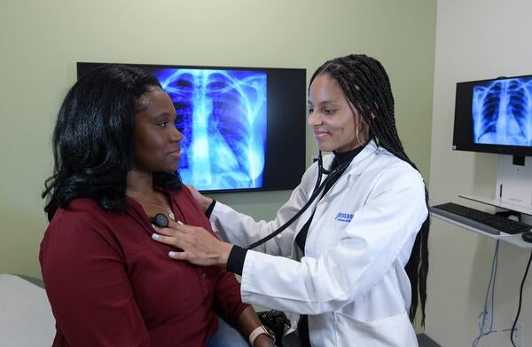 student checking the heart of a patient