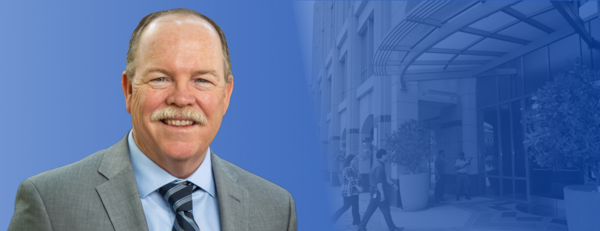 Tim Collins, CEO of UCR Health - in front of a blue background and the Citrus Tower facility