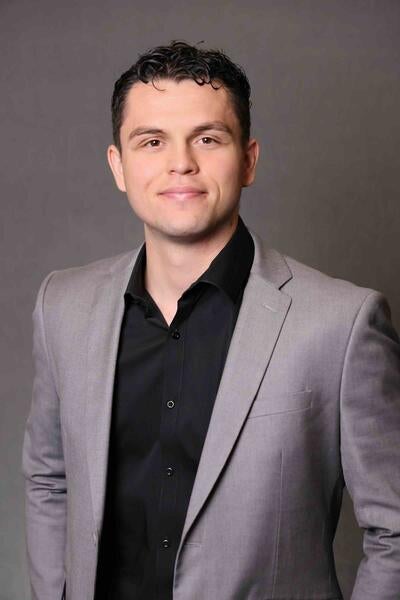 Javier Prieto in a gray suit against a dark gray background