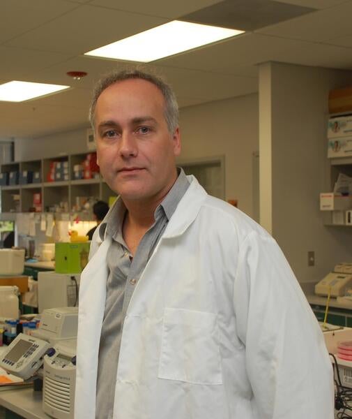 Marcus Kaul, PhD standing in a white coat