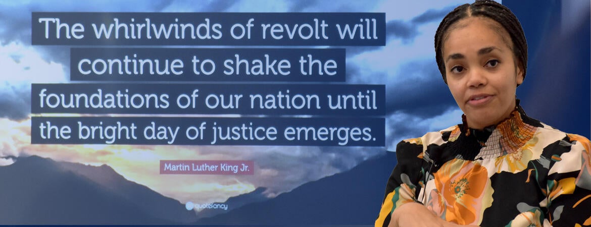 a picture of Dr. Gabrielle Pina in front of a quote from Dr. Martin Luther King, Jr. that reads "The whirlwinds of revolt will continue to shake the foundations of our nation until the bright day of justince emerges.
