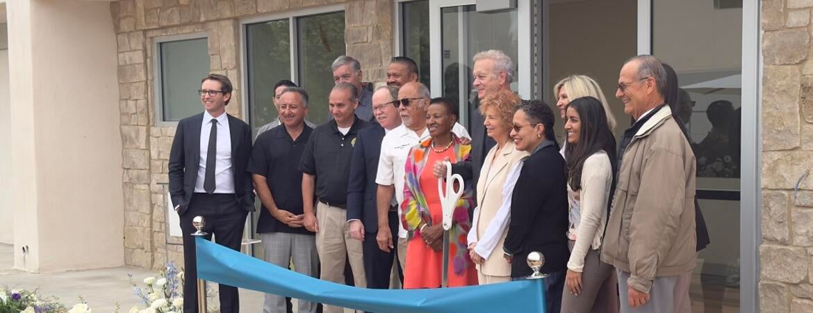 Dean Deas, Tim Collins, and Lisa Fortuna stand during the ribbon cutting.