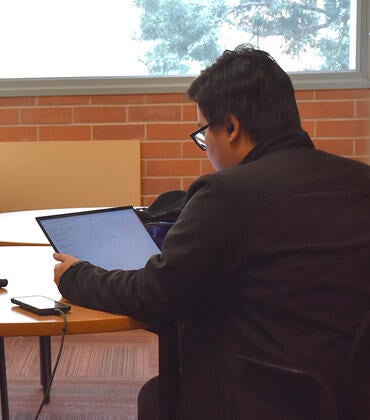 A UCR Medical Student uses his laptop in a student lounge.