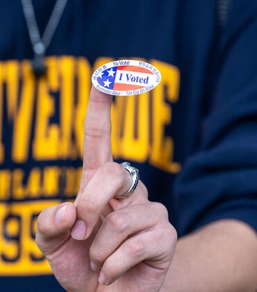 a person wearing a ucr shirt with an I voted sticker on their finger.