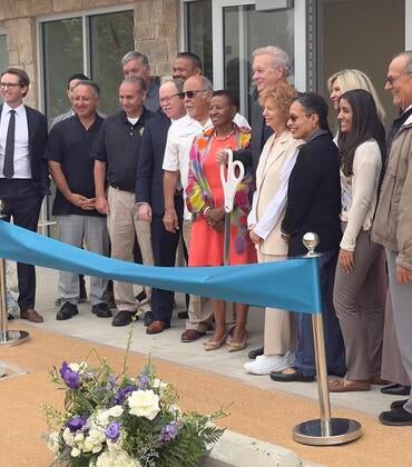 Dean Deas, Tim Collins, and Lisa Fortuna stand during the ribbon cutting.
