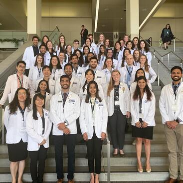 Group of students in white coats standing on steps