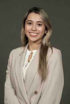 Pamela Munoz wearing a beige jacket against a dark gray background